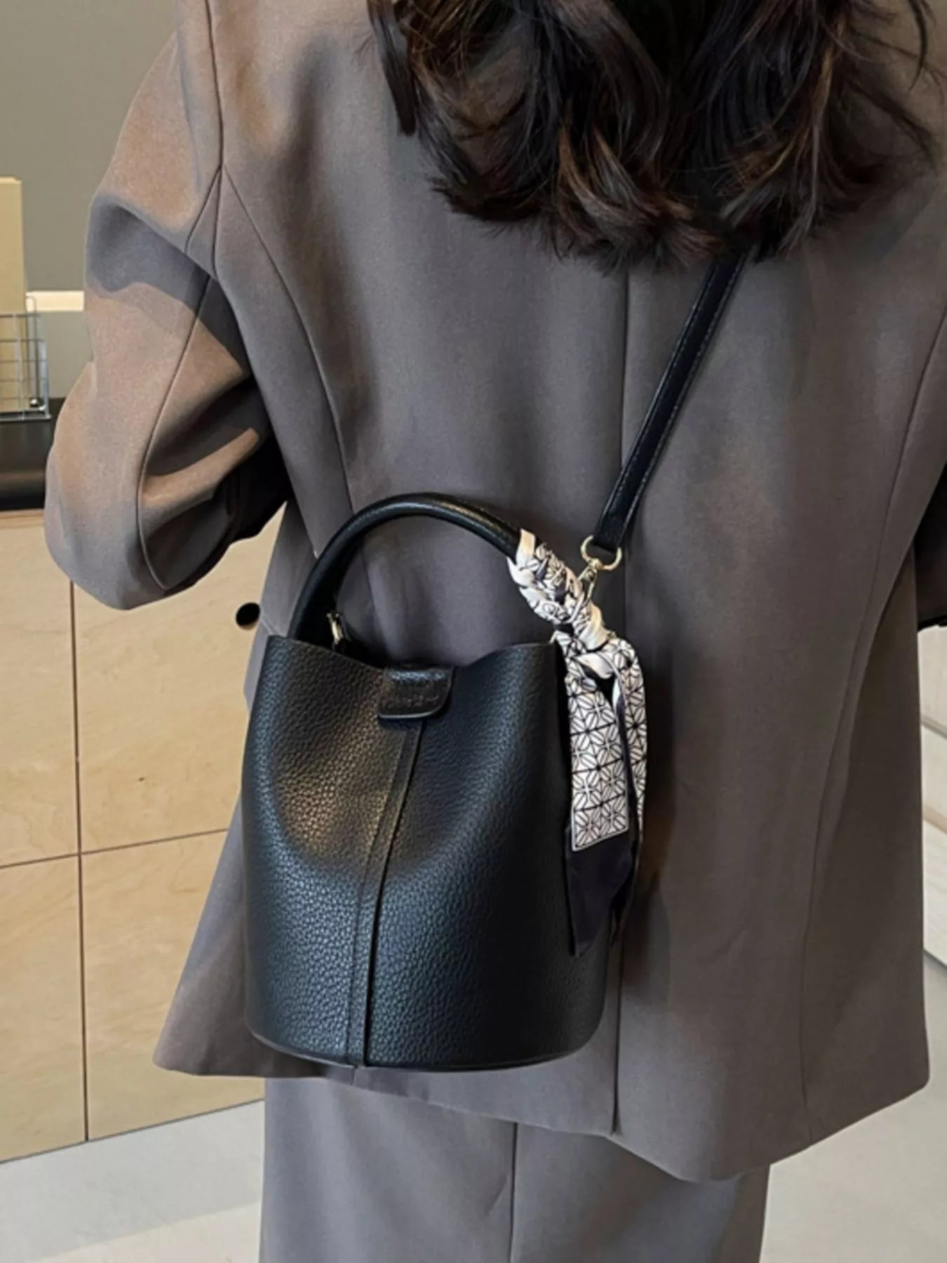 Leather bucket crossbody bag with adjustable strap and sleek design, featuring a rich brown leather finish.