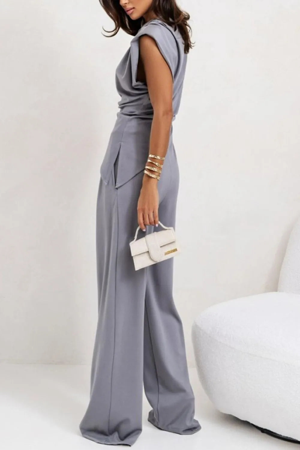 Draped sleeveless asymmetric top and matching pants set by Trendsi, featuring flowing fabric and modern design.