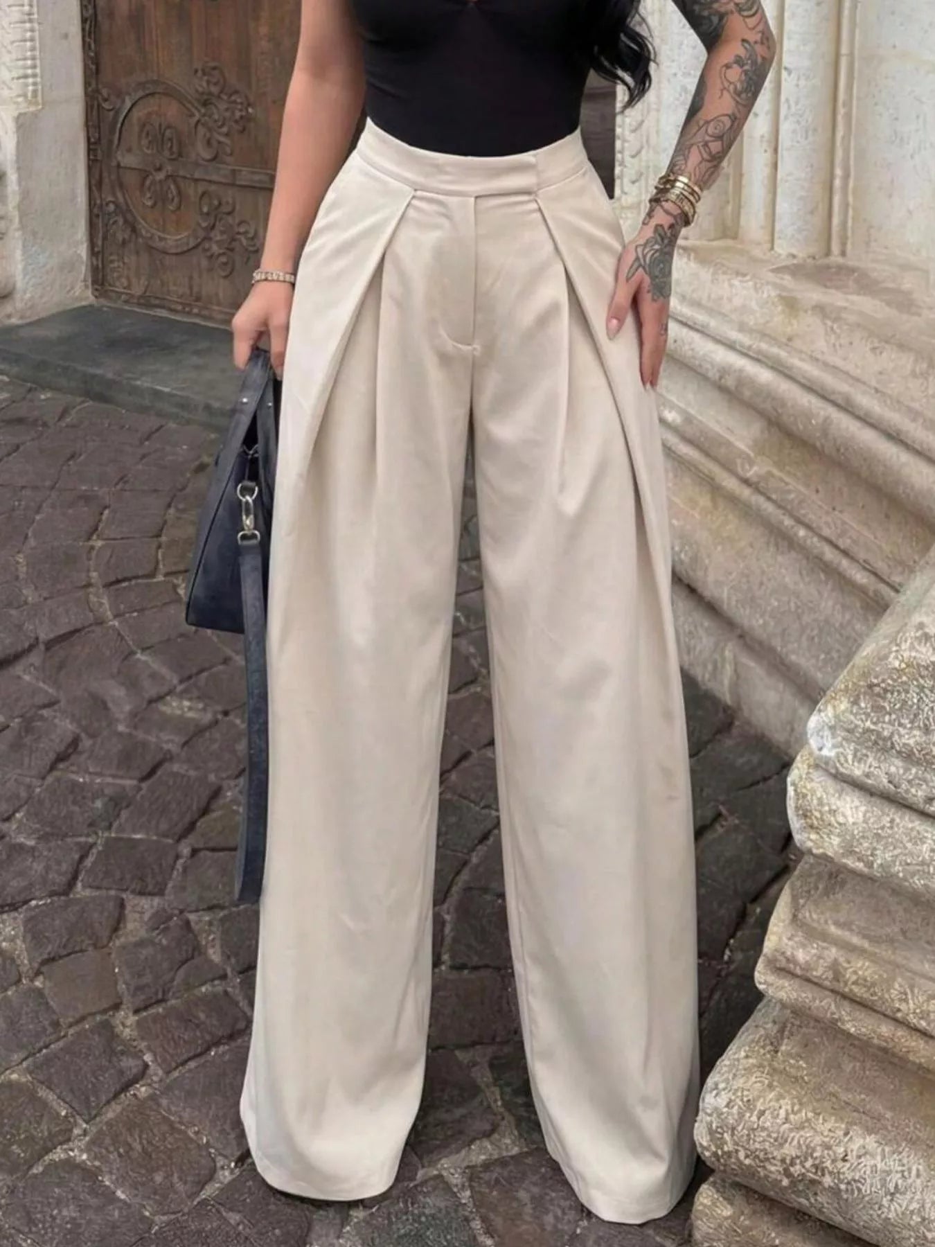 Wide-leg pleated trousers by Trendsi featuring a high-waisted fit, shown on a model with a relaxed, stylish look.