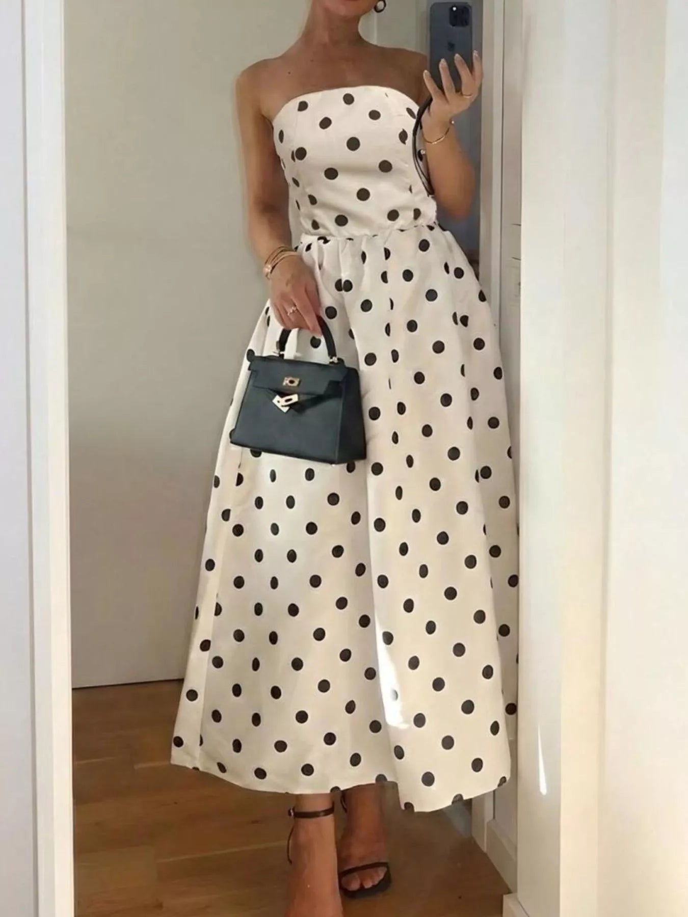 Polka dot strapless midi dress by Trendsi featuring a fitted bodice and flowing skirt in black and white polka dot pattern.