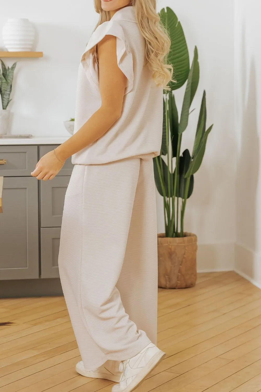 Textured ruffled sleeve zipped top and wide leg pants set by Trendsi, shown on a model with stylish design and fabric details.
