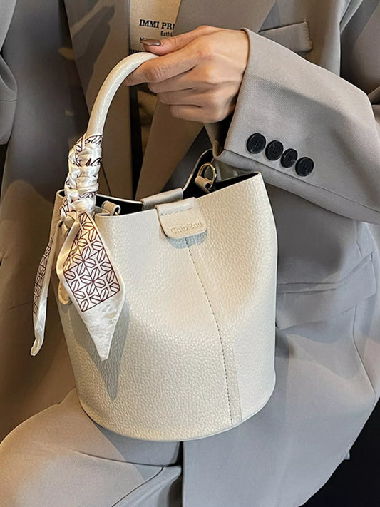 Leather bucket crossbody handbag in tan with adjustable strap and gold hardware, stylish and versatile for everyday use.