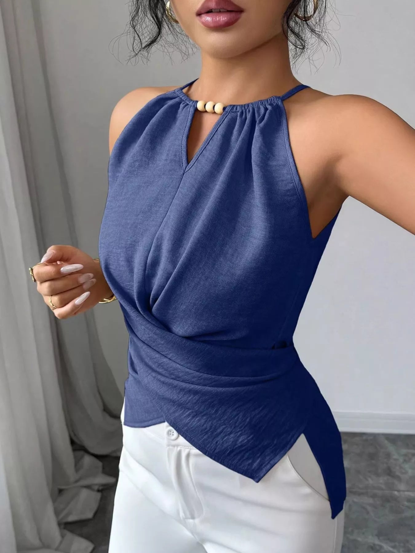 Halter neck crisscross cami top from Trendsi, featuring a stylish design with adjustable straps and a fitted silhouette.