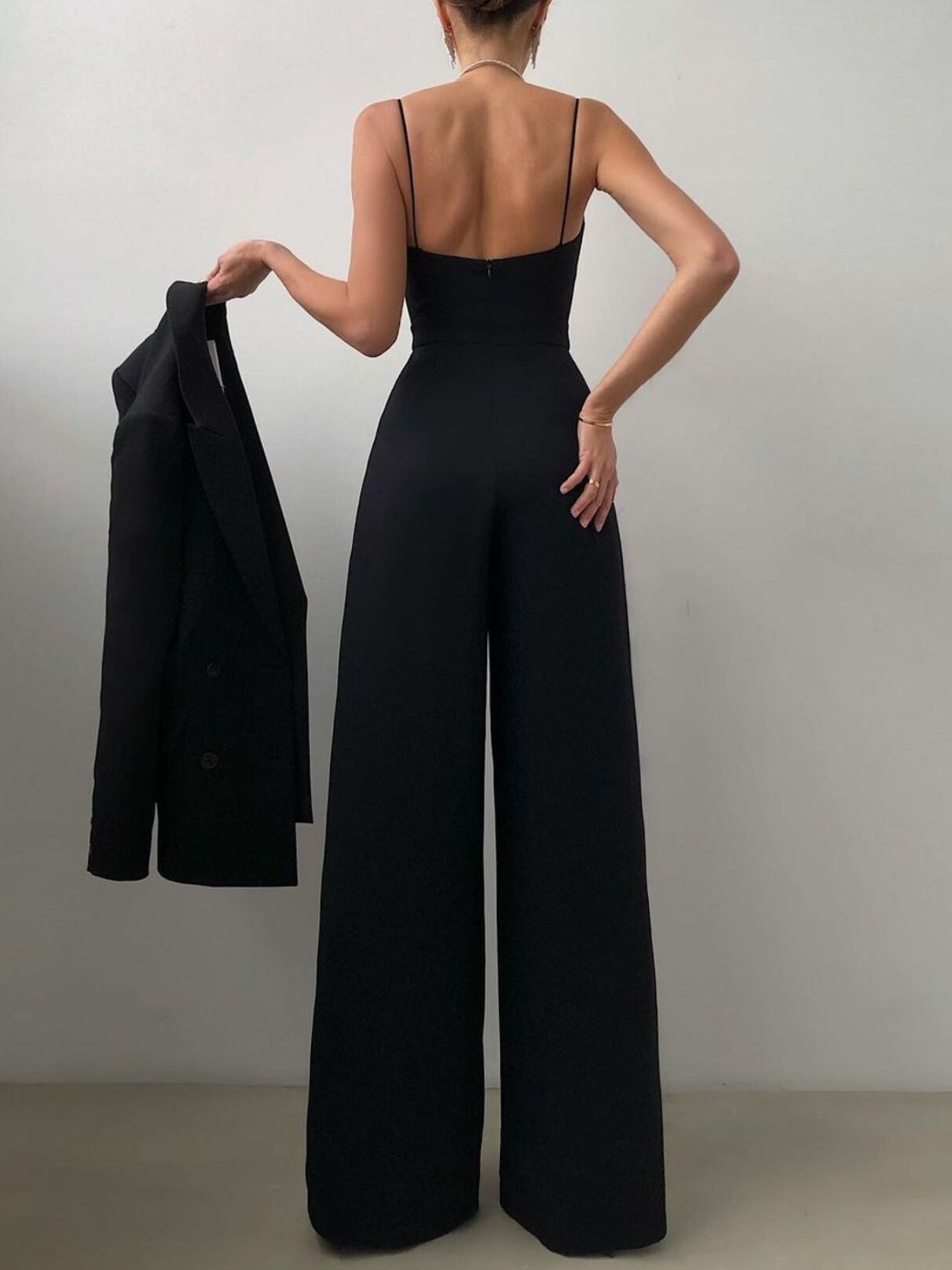 Trendsi spaghetti strap wide leg jumpsuit hanging on a hanger, showcasing its flowing fabric and stylish design.
