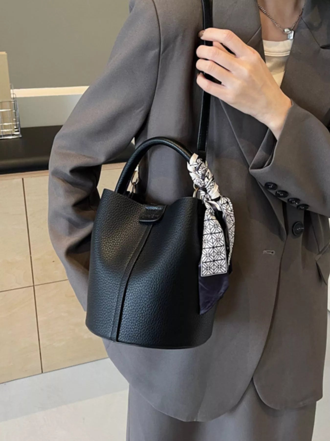 Leather bucket crossbody bag by Trendsi featuring a stylish, compact design with a leather strap and minimalist aesthetic.