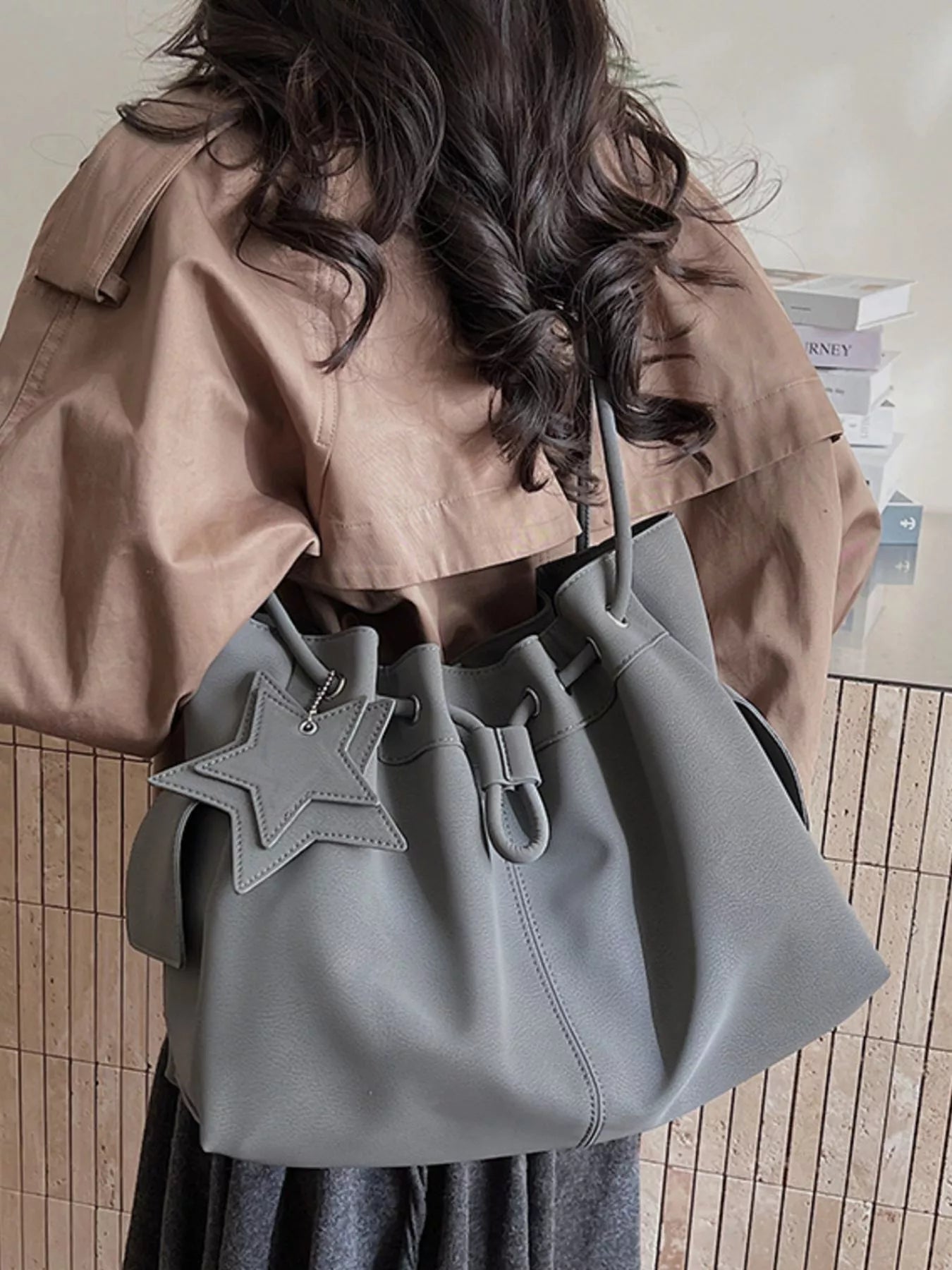 Black drawstring shoulder bag with star charm and trendy design, made by Trendsi, featuring a compact, stylish handbag with adjustable straps.
