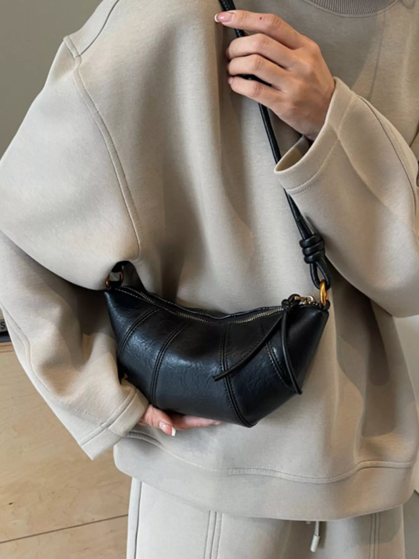 Croissant-shaped crossbody handbag by Trendsi, featuring a soft, foldable design with a gold chain strap and stylish details.
