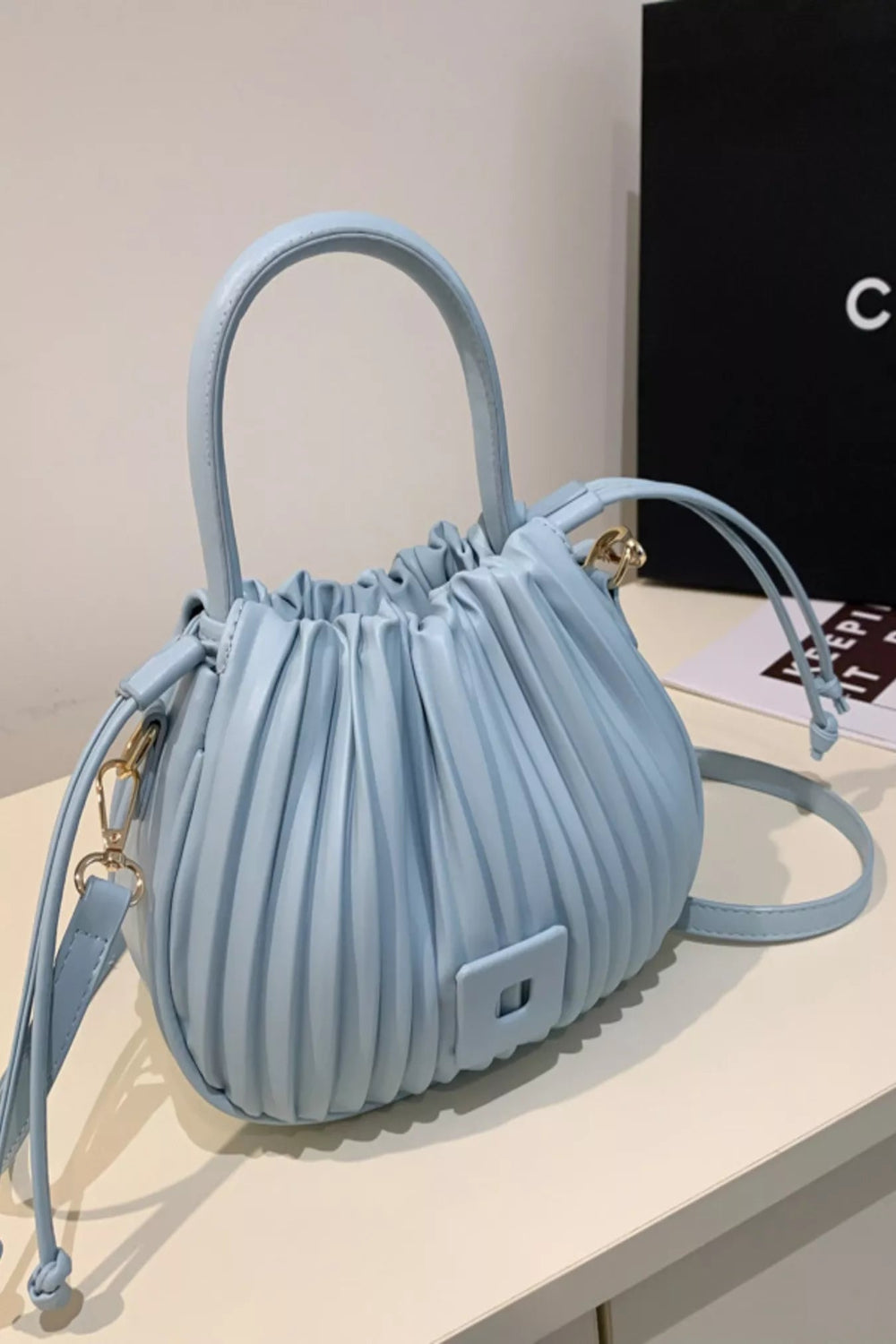 Pleated bucket crossbody bag by Trendsi, stylish handbag with a sleek design and adjustable strap, ideal for casual or chic outfits.