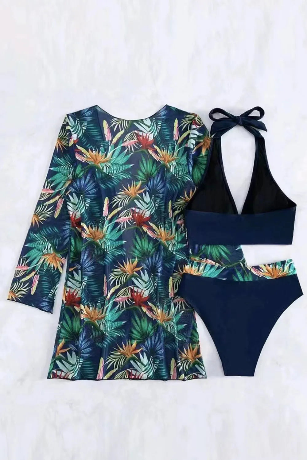Printed halter neck three-piece swim set by Trendsi, featuring a stylish swimwear design with top, bottom, and cover-up elements.
