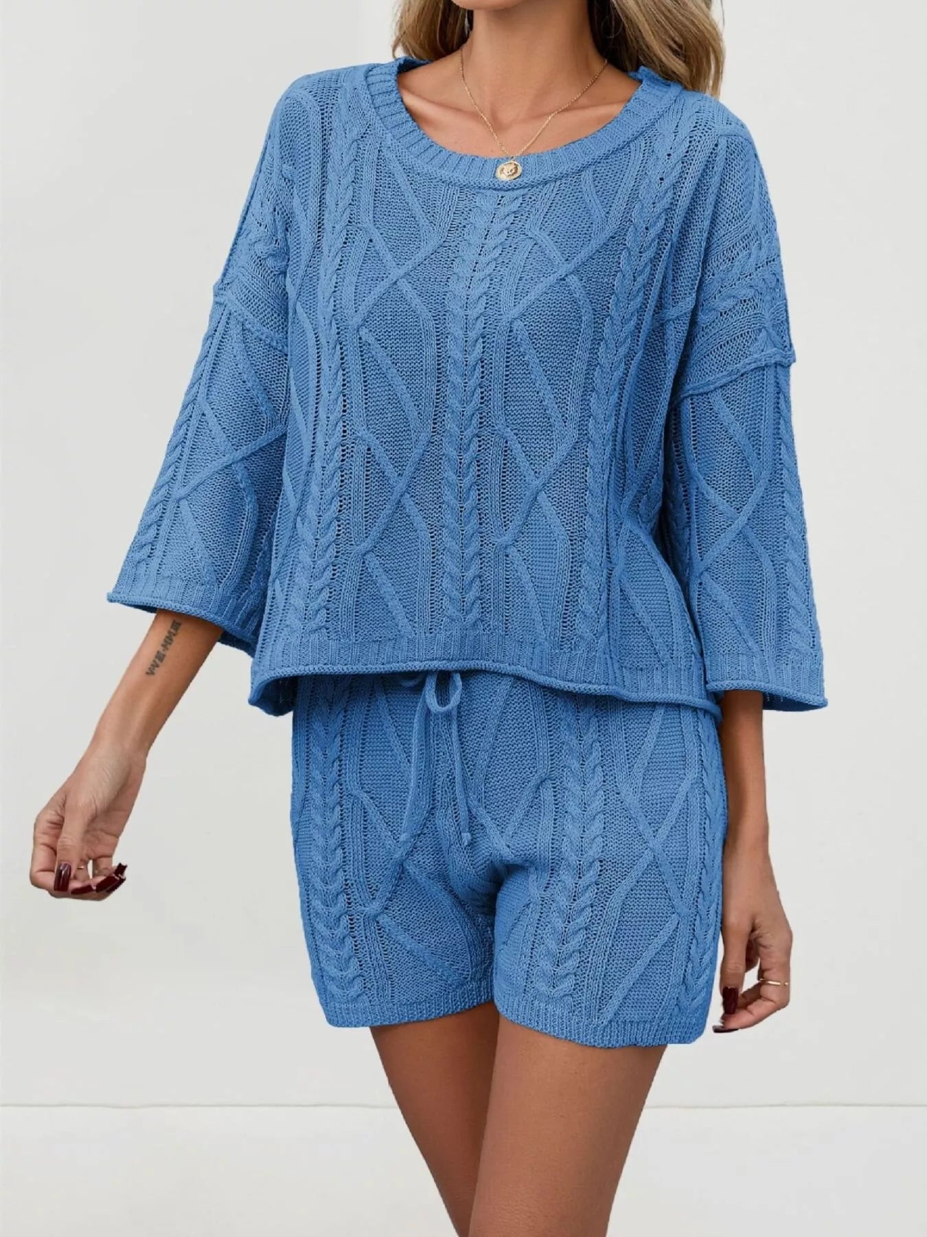 Cable knit round neck top and shorts sweater set by Trendsi, featuring a cozy knit fabric in a stylish matching design.