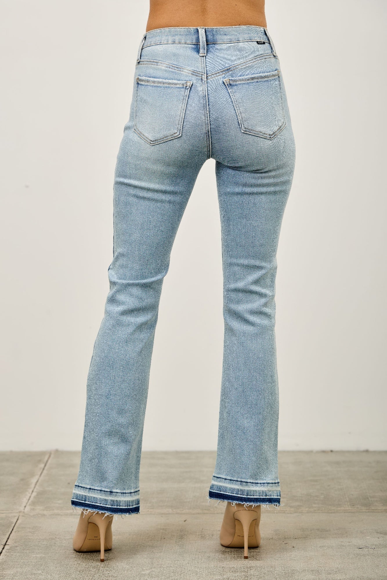 Mid-rise flare jeans with a released hem from Toshe Women's Fashions, shown on a model, featuring a fitted waist and stylish flare leg.