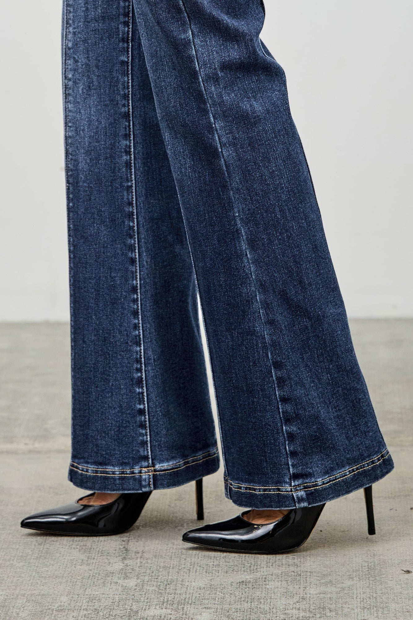 Toshe Women's Fashions high rise boot cut jeans with seam detail, shown on a model, featuring a classic denim style and fitted waist.