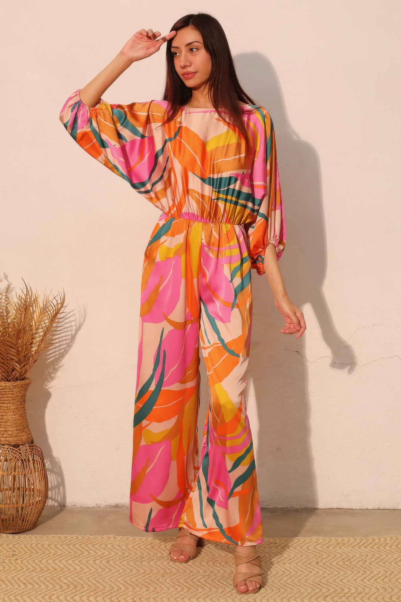 Toshe Women's Fashions Isla Tropical satin boat neck blouson jumpsuit laid flat, showcasing its relaxed fit and smooth satin fabric.
