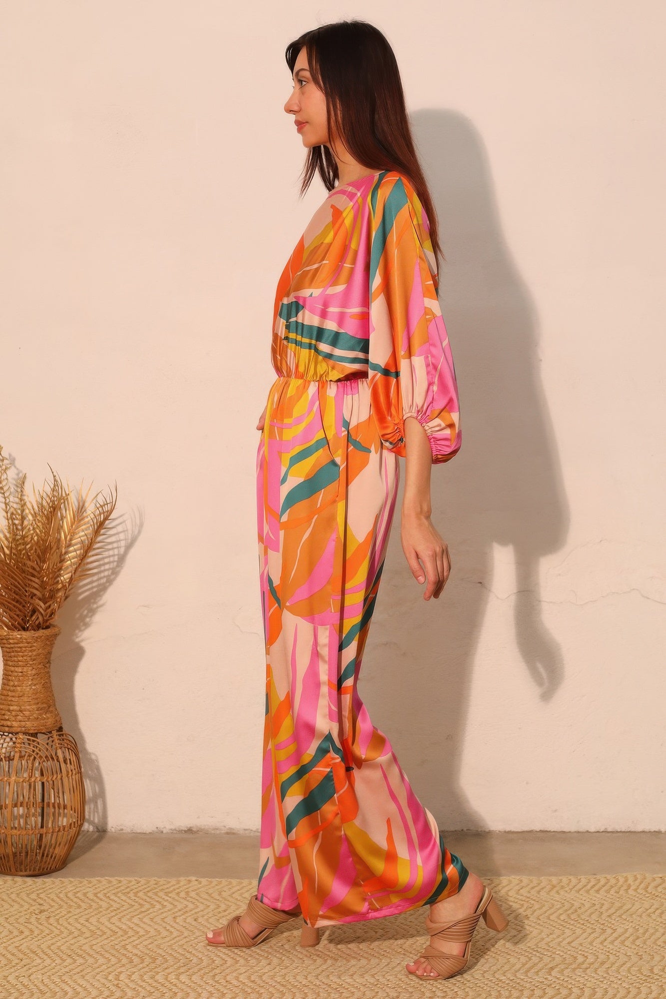 Toshe Women's Fashions Isla Tropical satin boat neck blouson jumpsuit displayed on a model with relaxed fit and tropical print fabric.