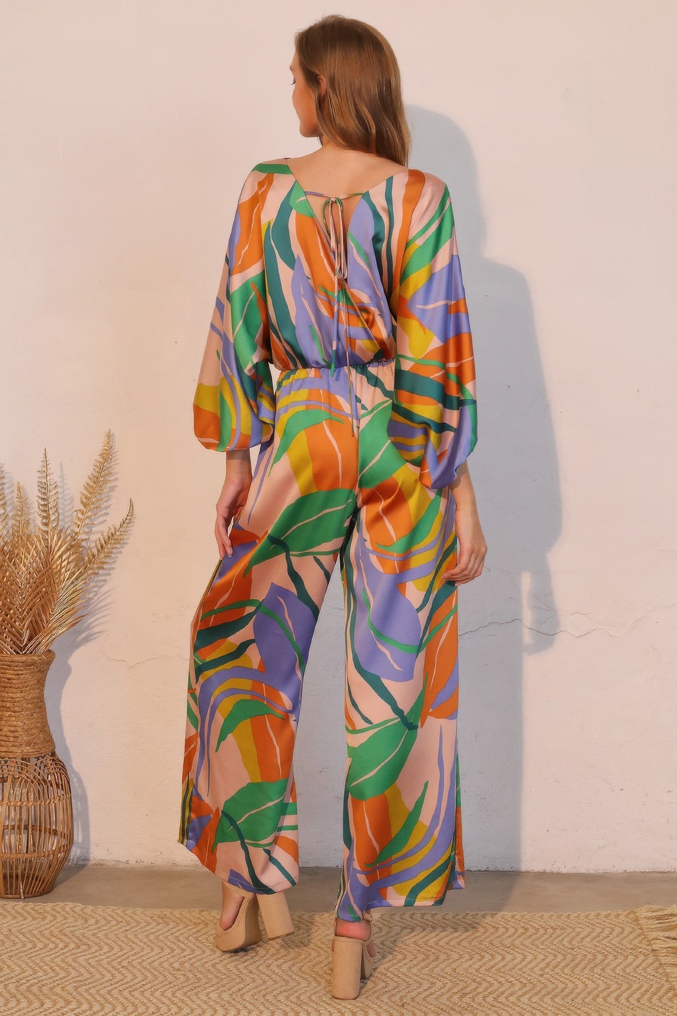 Toshe Women's Fashions Isla Tropical satin boat neck blouson jumpsuit displayed on a hanger, featuring a relaxed fit and tropical print.