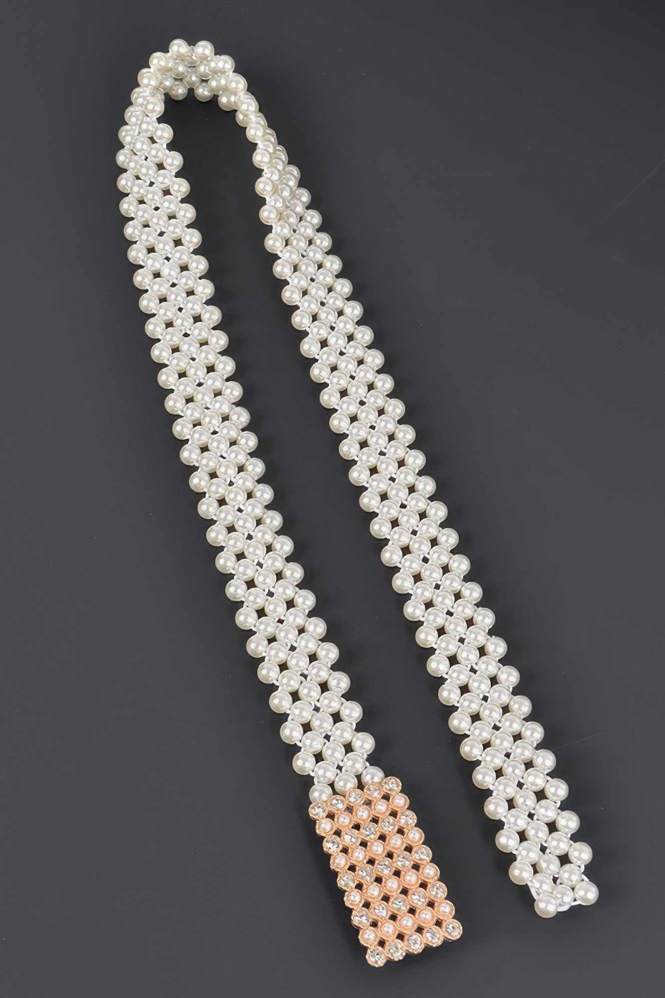 Elastic pearl belt with a sleek design, featuring a row of white pearls on a stretchable band, perfect for stylish outfits.