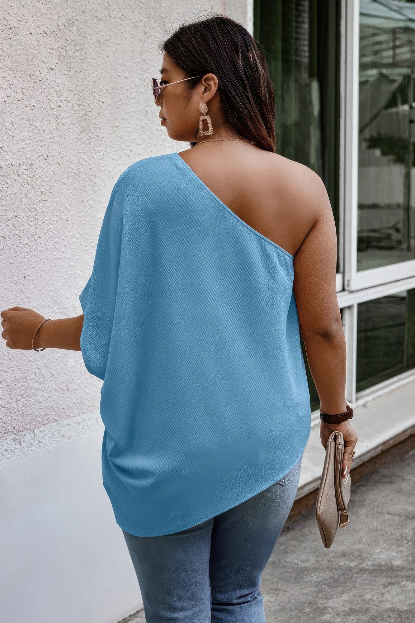 Loose fit one-shoulder shirt by Toshe Women's Fashions, shown in a relaxed style with draped fabric.