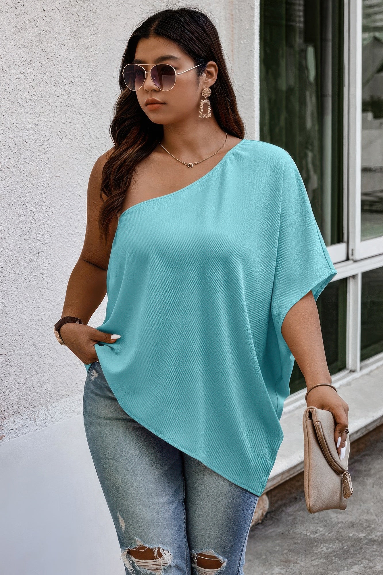 Loose fit one-shoulder shirt by Toshe Women’s Fashions, shown in a relaxed style with draped fabric and casual fit.
