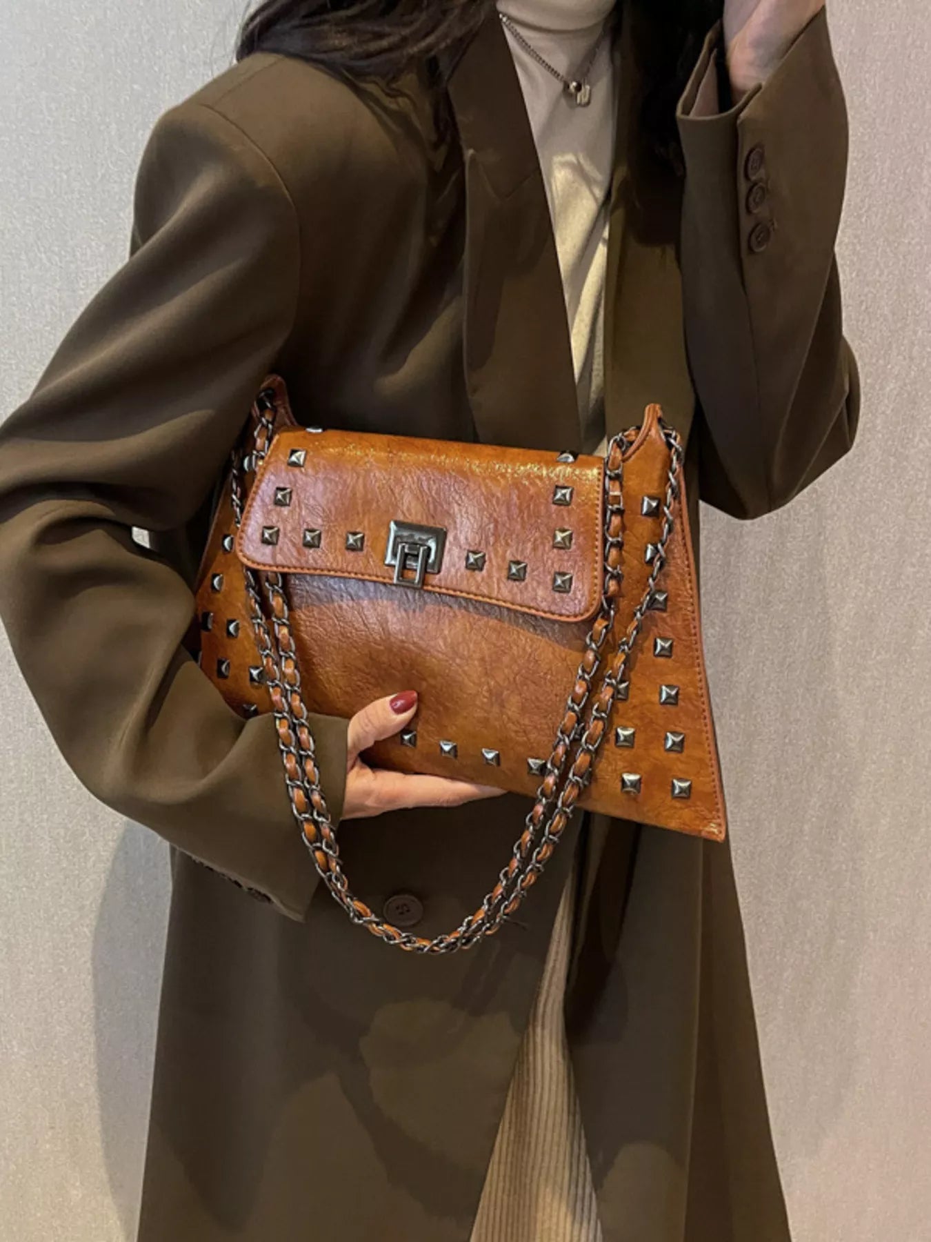 Black studded flap chain shoulder handbag with silver accents, featuring a structured design and adjustable strap.
