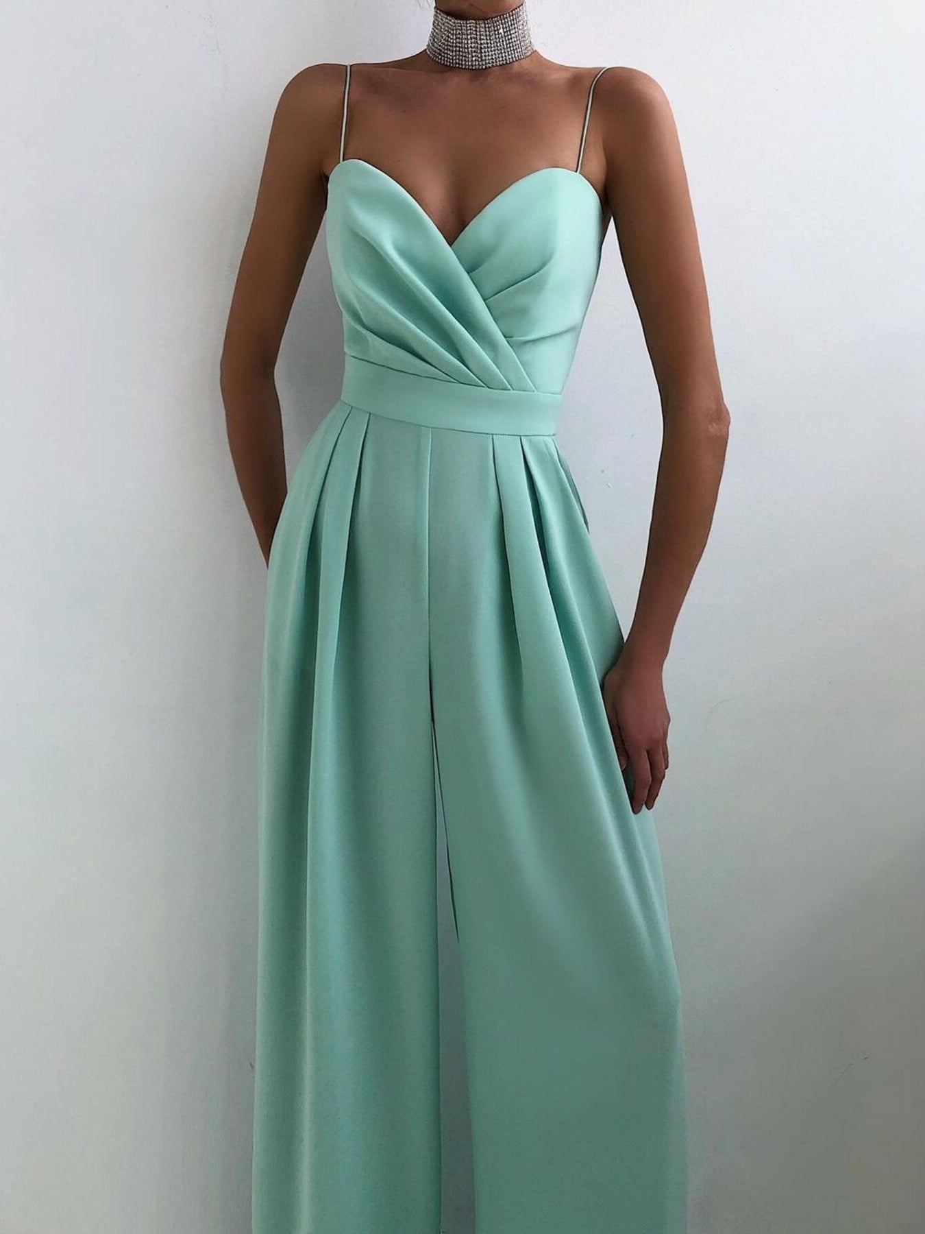 Beige spaghetti strap wide leg jumpsuit by Trendsi, featuring a fitted bodice and flowing wide-leg pants on a model.