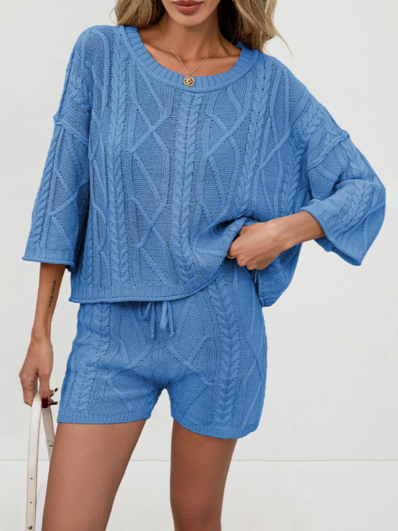 Cable knit round neck top and shorts sweater set by Trendsi, featuring a cozy, textured knit fabric in a stylish matching design.