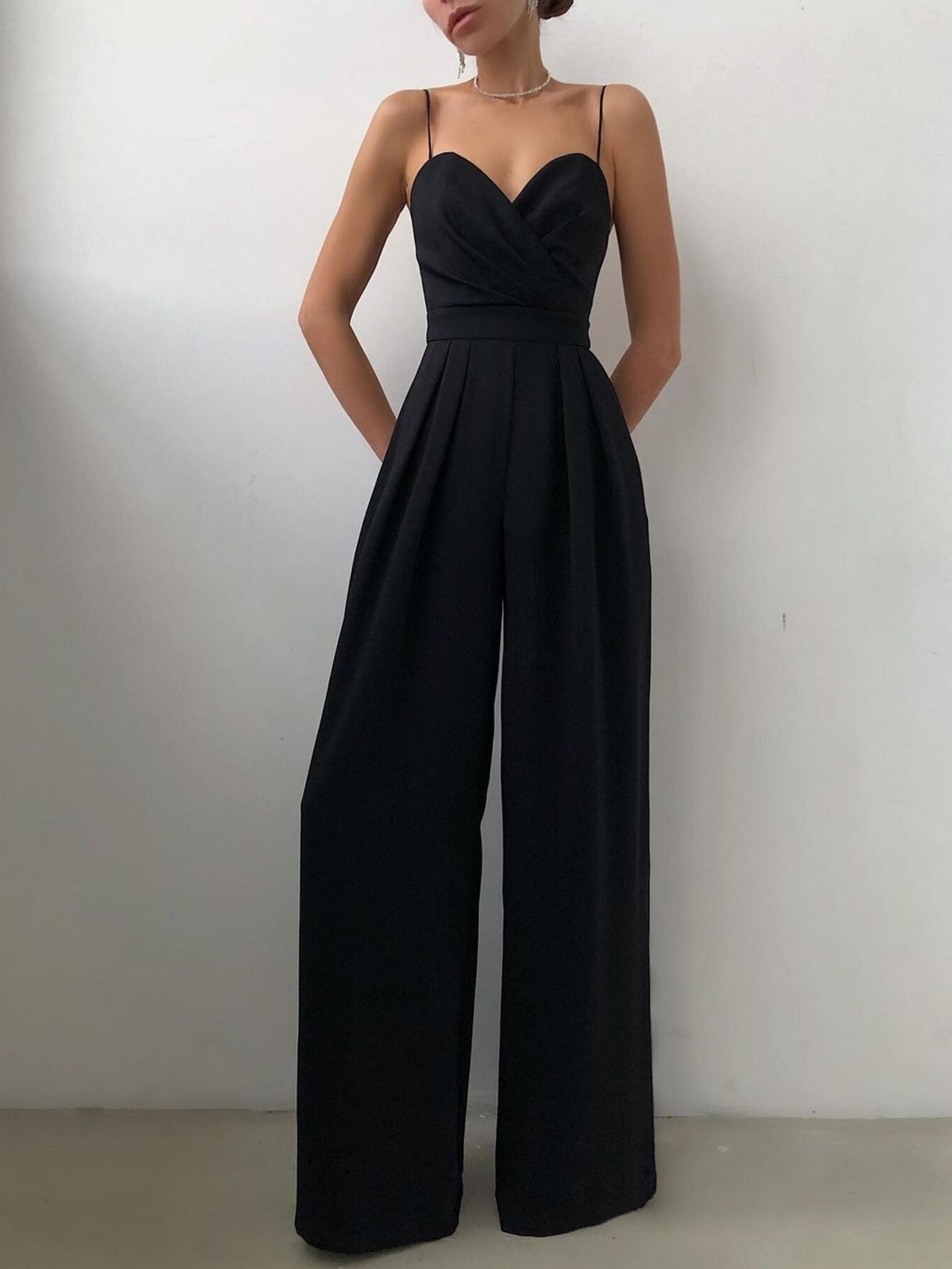 Trendsi spaghetti strap wide-leg jumpsuit displayed on a hanger with a casual, flowing design and neutral color.