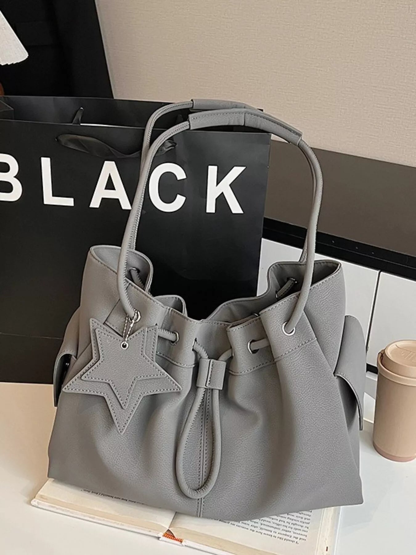 Drawstring shoulder bag with star charm from Trendsi, featuring a stylish design and adjustable strap, perfect for casual wear.