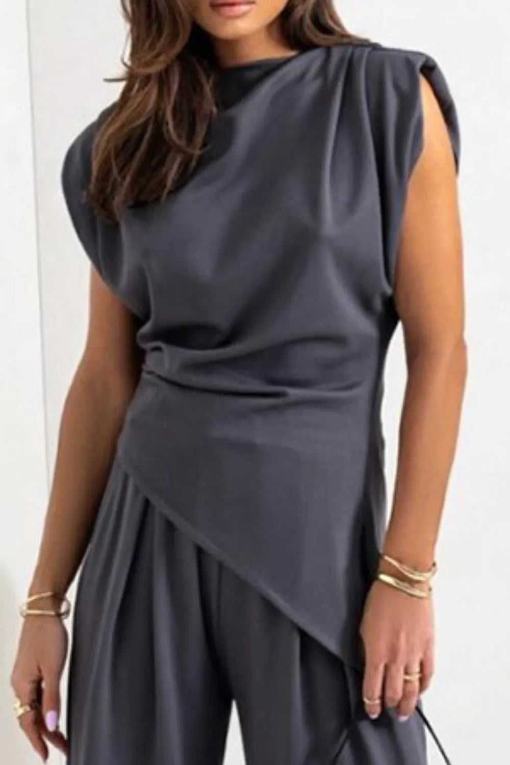 Draped sleeveless asymmetric top and matching pants set by Trendsi, featuring flowing fabric and modern design.