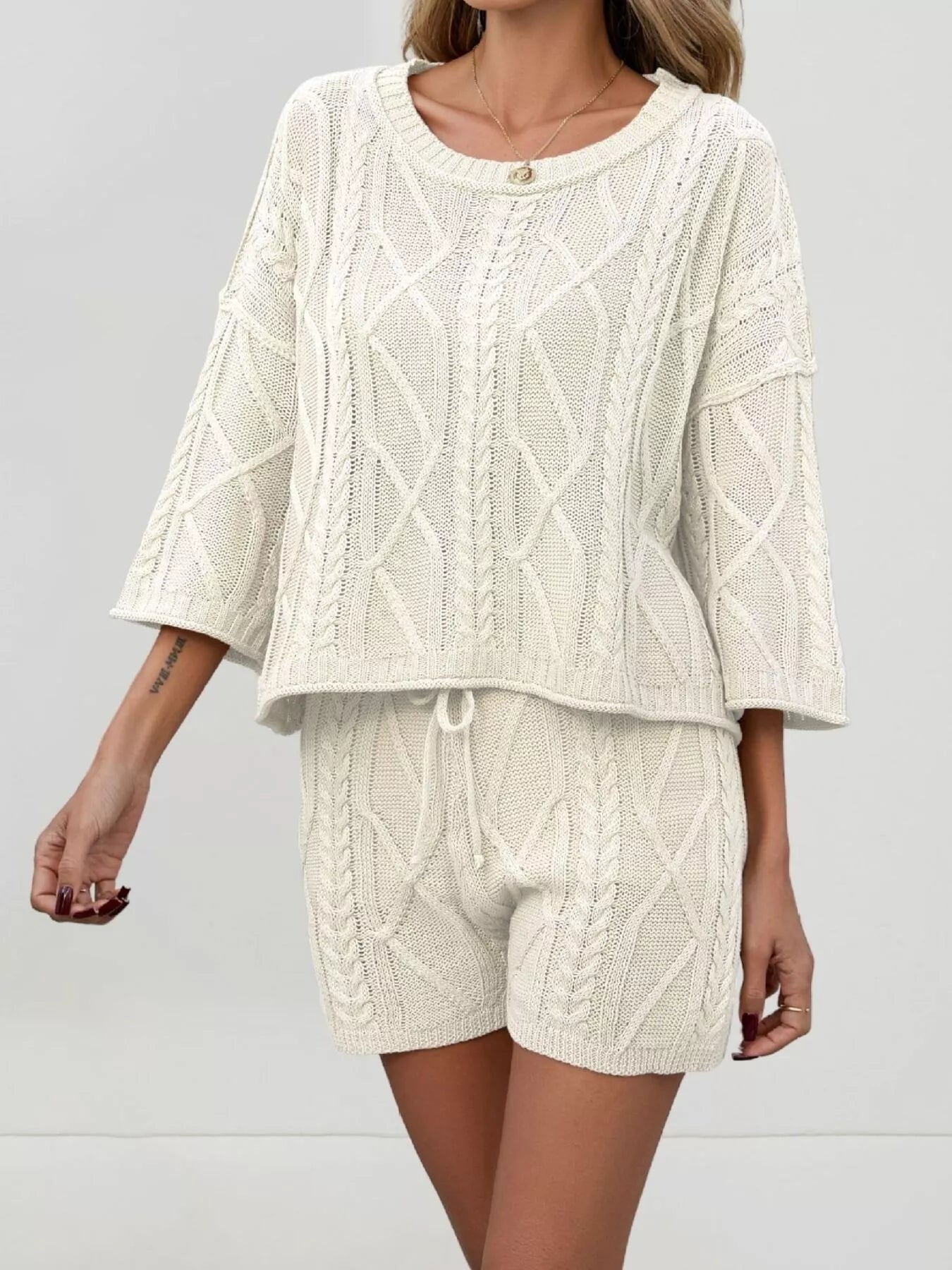 Trendsi cable knit round neck top and shorts sweater set, featuring a cozy, textured knit fabric in a stylish matching two-piece.