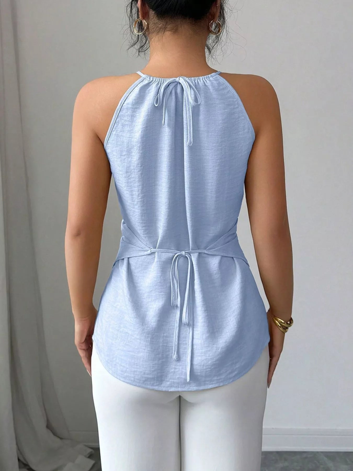Halter neck crisscross cami top from Trendsi featuring a fitted design with stylish straps and a sleek, modern look.