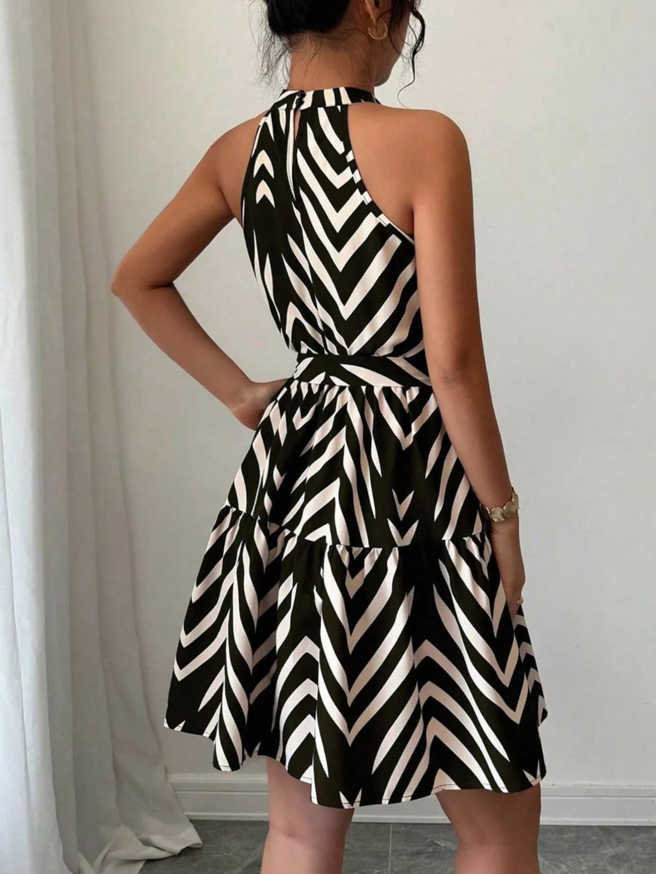 Zebra print halter neck dress with tie waist and ruffle hem, trendy women's dress by Trendsi, shown on a model.