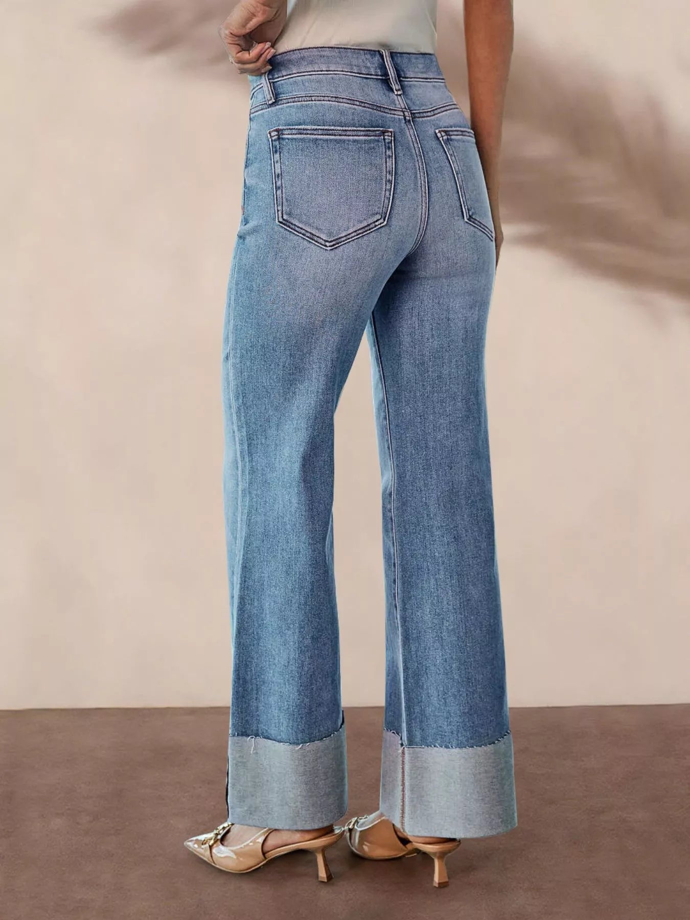 Distressed high-waisted flare jeans in denim with frayed details, styled by Trendsi, displayed on a model.